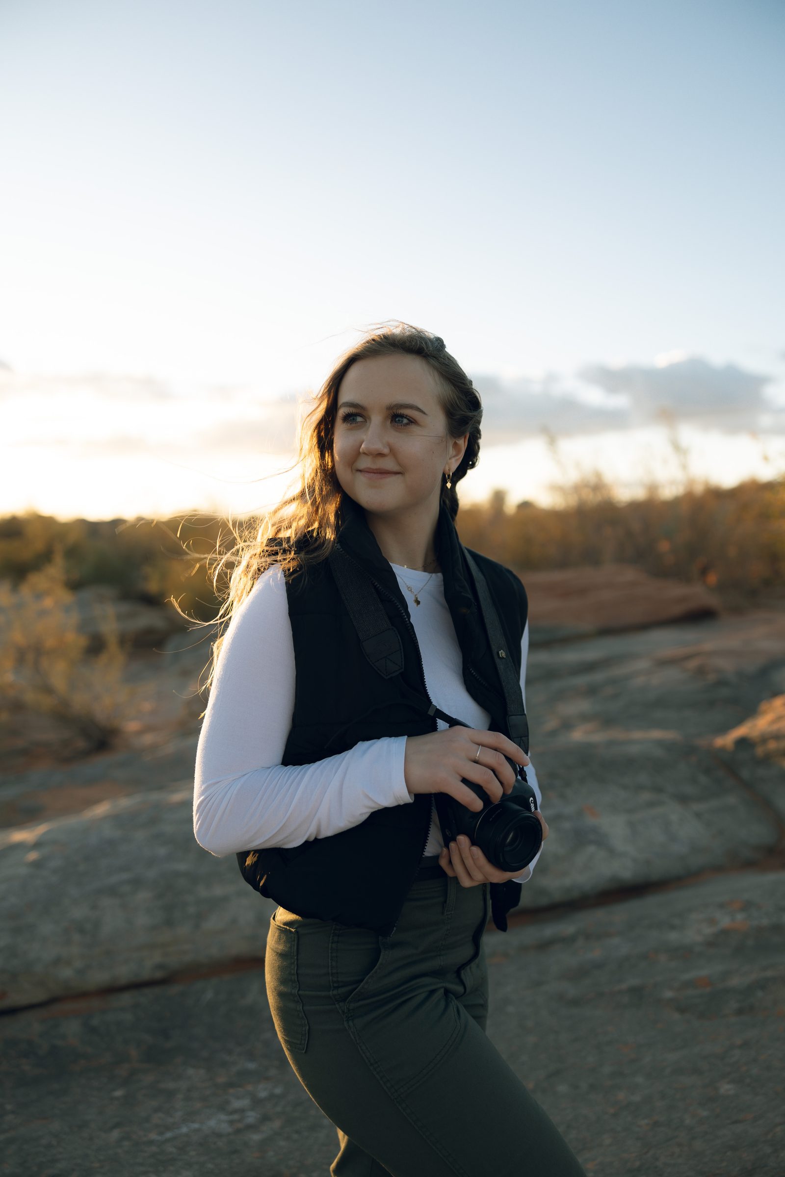 Sydney smiling outdoors, red rock and lake in the background