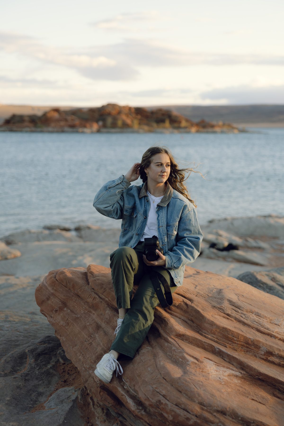 Sydney sitting on red rock with her camera, smiling