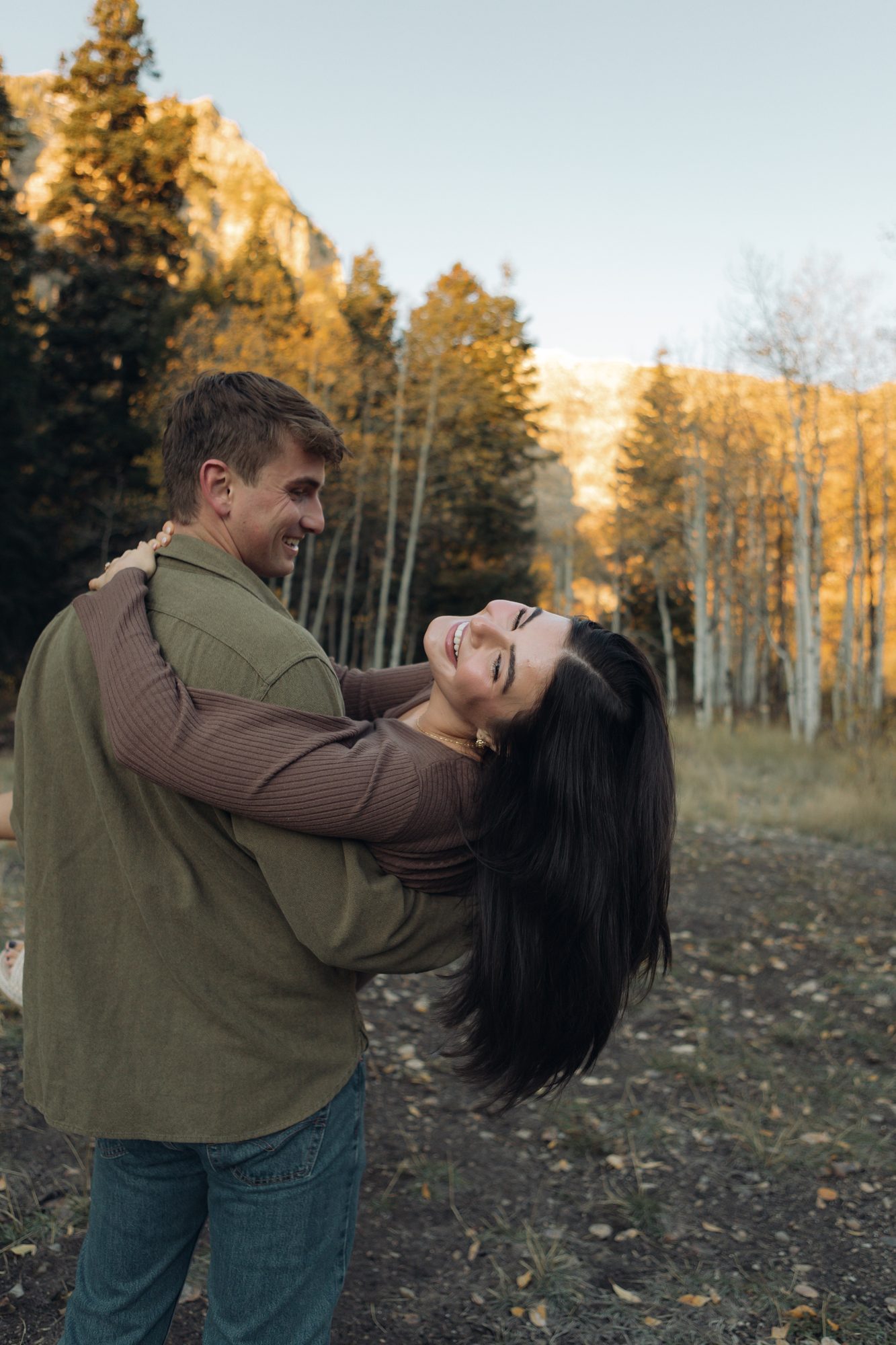 Couple laughing together among golden aspen trees