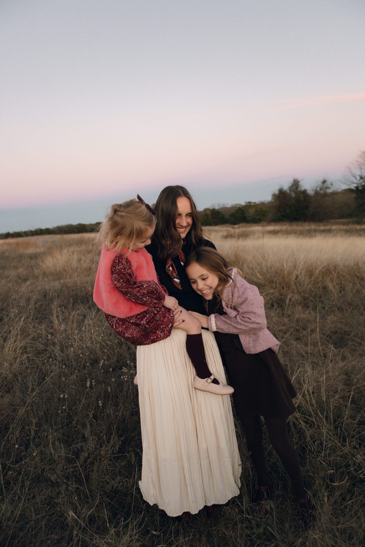 Mother laughing with her two daughters outdoors