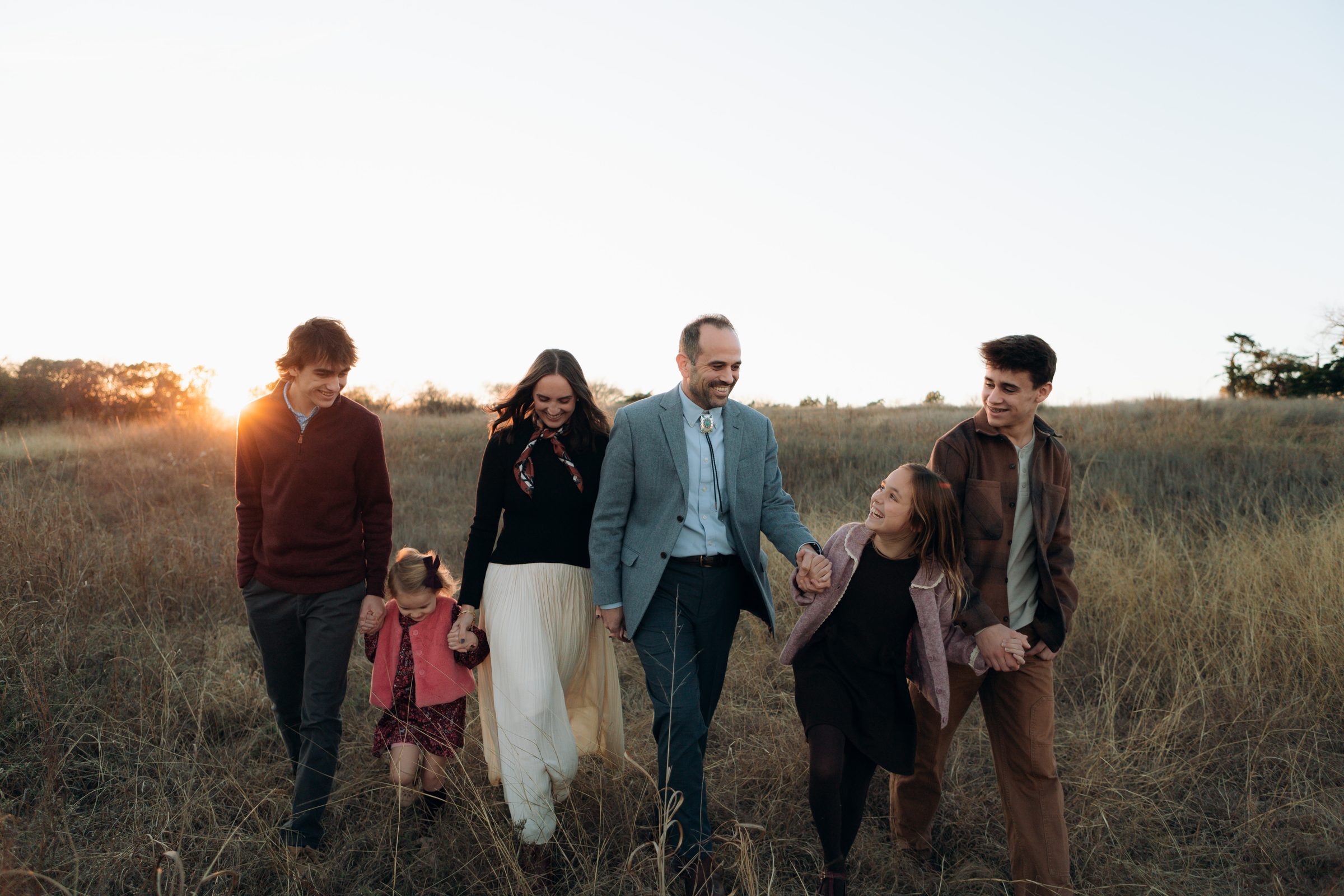 Large family group portrait in a golden field at sunset