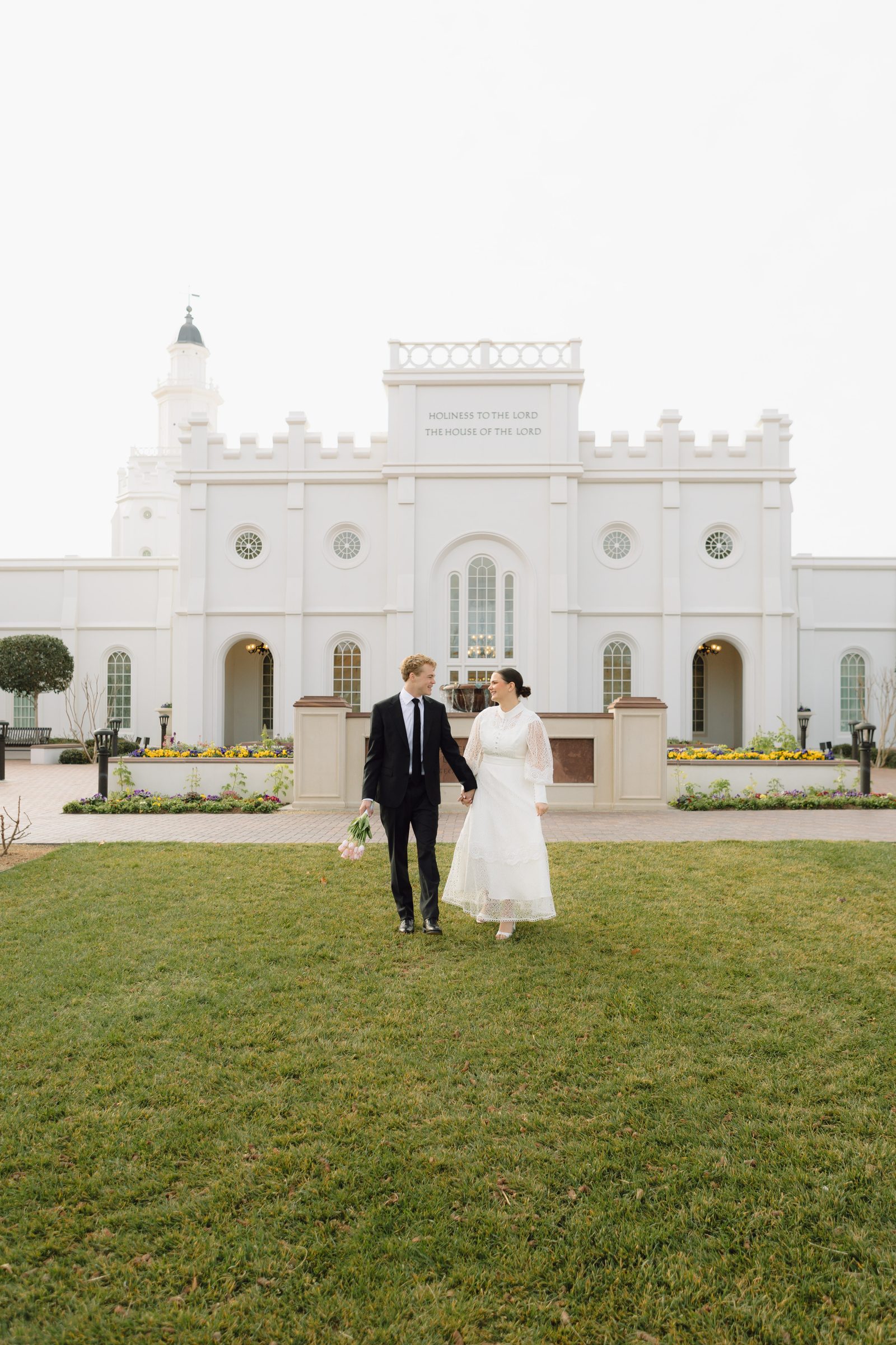 Bride and groom walking toward the temple under a dramatic sky